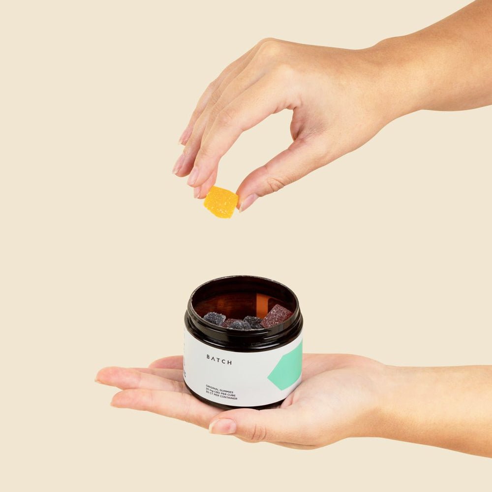 hand reaching for a mango cbd gummy out of the container